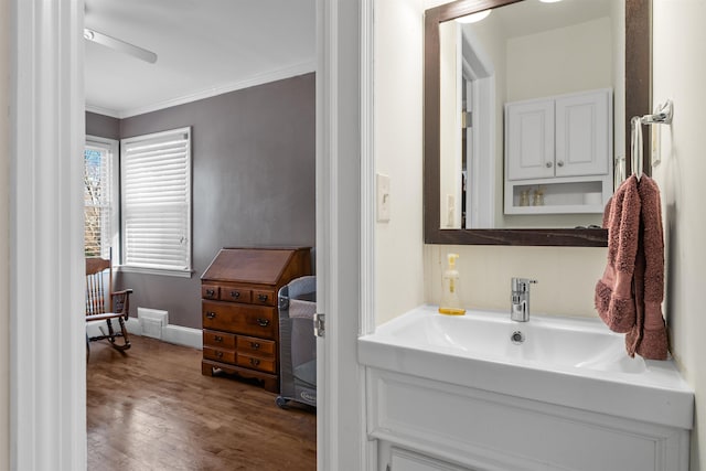 bathroom featuring wood-type flooring, ceiling fan, ornamental molding, and sink