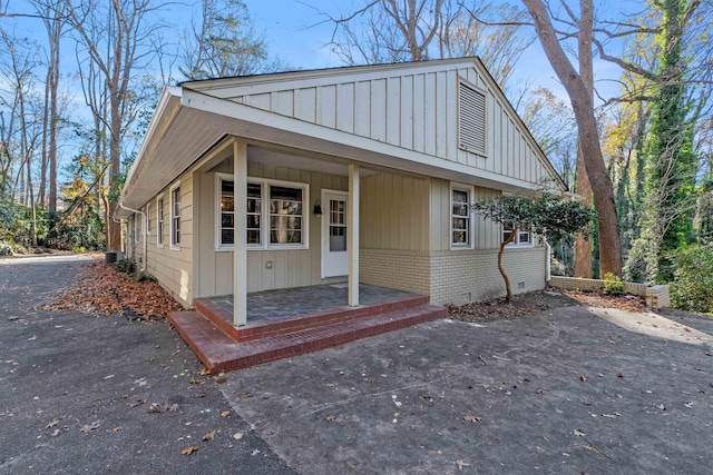 view of front of home featuring covered porch, board and batten siding, and brick siding