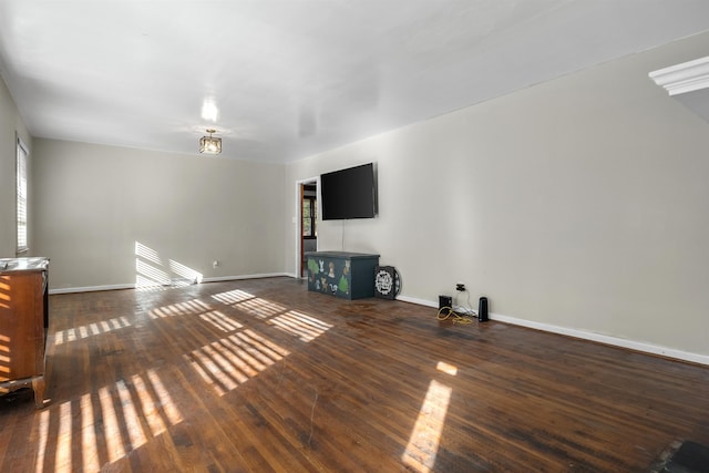 unfurnished living room featuring plenty of natural light and dark hardwood / wood-style flooring