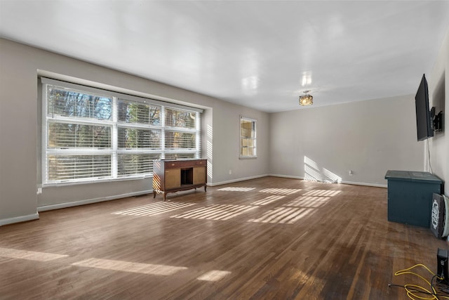 unfurnished living room with baseboards and wood finished floors