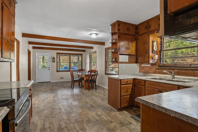 kitchen with backsplash, beam ceiling, brown cabinetry, and a sink