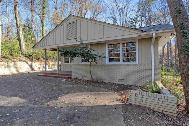 view of front of property featuring crawl space, board and batten siding, and brick siding