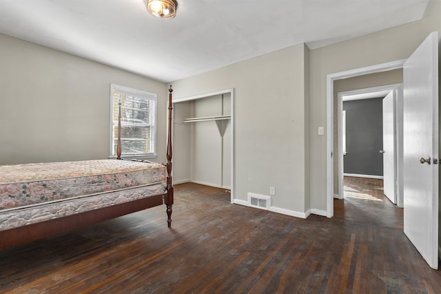 bedroom featuring a closet, wood-type flooring, visible vents, and baseboards