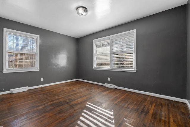 spare room with baseboard heating, baseboards, visible vents, and hardwood / wood-style floors