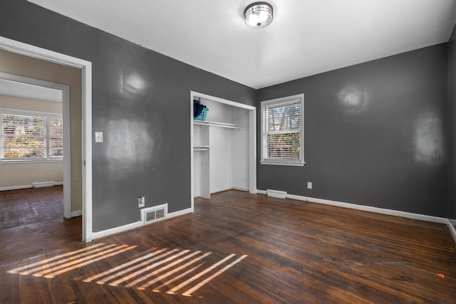 unfurnished bedroom featuring a closet, wood finished floors, visible vents, and baseboards