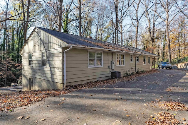 view of property exterior featuring board and batten siding, a shingled roof, and a chimney