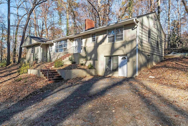 exterior space with stairway, brick siding, and a chimney