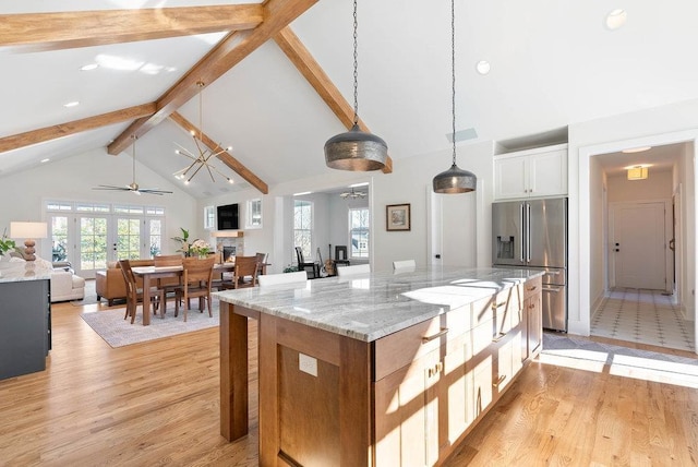 kitchen featuring hanging light fixtures, a kitchen island, light stone counters, high end fridge, and white cabinets