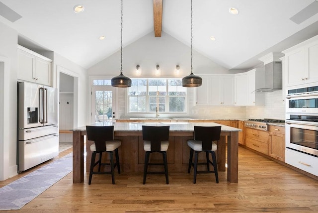 kitchen featuring white cabinetry, wall chimney exhaust hood, stainless steel appliances, and a kitchen island