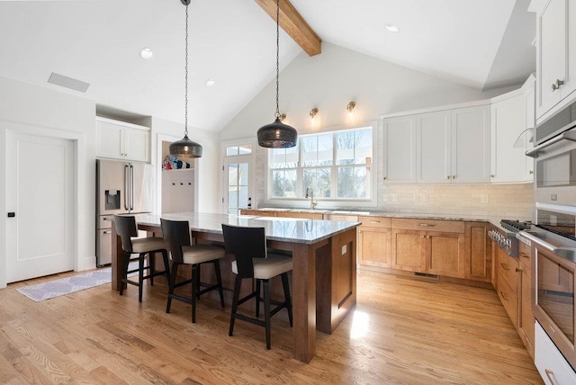 kitchen with a center island, light stone counters, white cabinetry, and light wood-type flooring