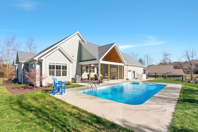 back of house featuring a patio, a fenced in pool, and a lawn