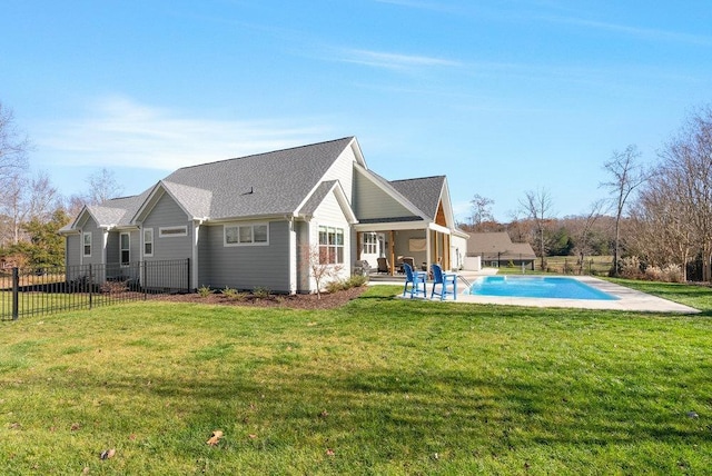 rear view of house with a yard, a fenced in pool, and a patio area