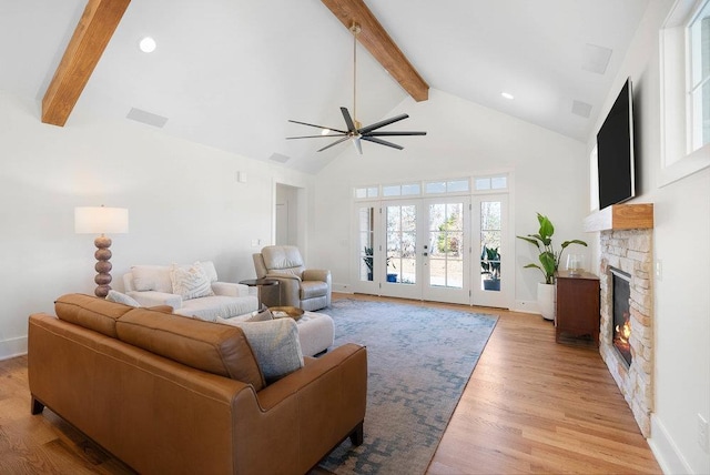 living room featuring high vaulted ceiling, ceiling fan, a fireplace, beam ceiling, and light hardwood / wood-style floors