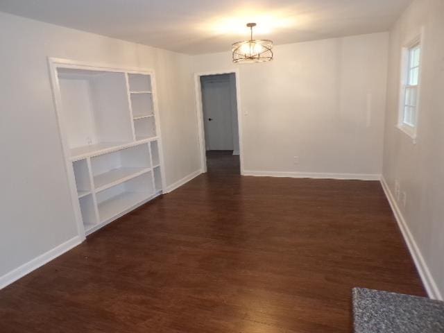 empty room featuring an inviting chandelier and dark wood-type flooring