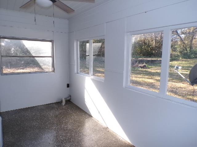 unfurnished sunroom featuring ceiling fan and plenty of natural light