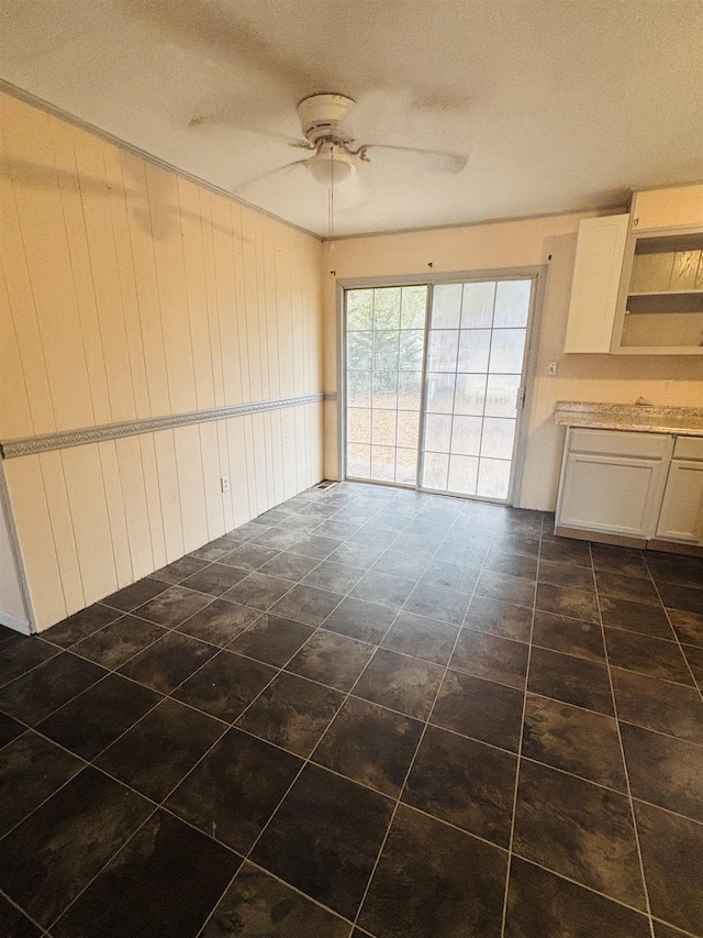 spare room featuring wooden walls, ceiling fan, and a textured ceiling