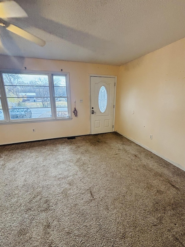 carpeted entrance foyer with ceiling fan and a textured ceiling