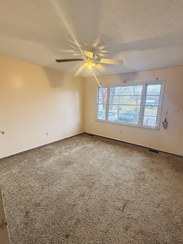 spare room with ceiling fan, carpet flooring, and a textured ceiling