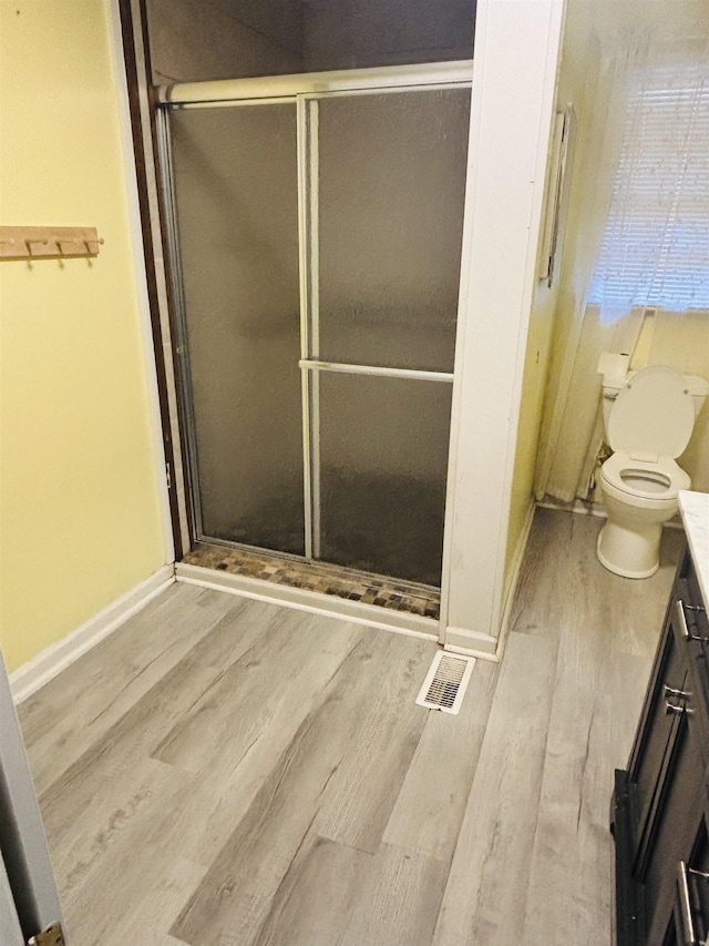 bathroom with an enclosed shower, hardwood / wood-style floors, vanity, and toilet