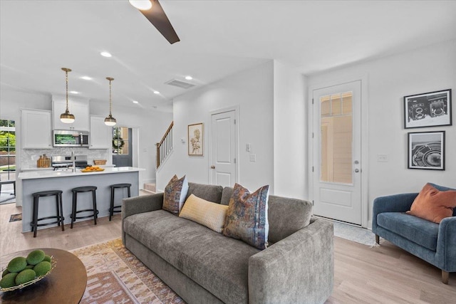 living room with ceiling fan, light hardwood / wood-style floors, a wealth of natural light, and sink