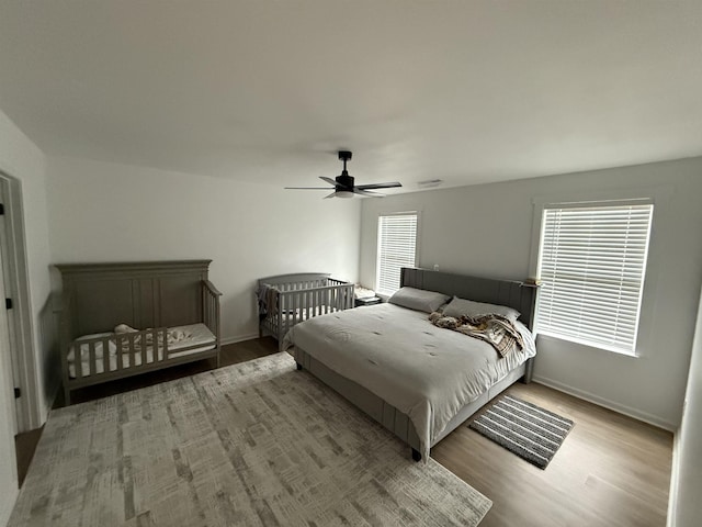 bedroom with ceiling fan, light wood-type flooring, and multiple windows