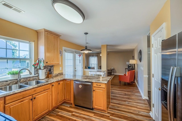 kitchen featuring sink, kitchen peninsula, a wealth of natural light, wood-type flooring, and stainless steel appliances