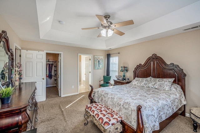 bedroom with a spacious closet, a closet, ceiling fan, and light carpet