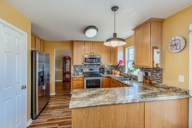 kitchen featuring sink, dark hardwood / wood-style flooring, kitchen peninsula, pendant lighting, and appliances with stainless steel finishes