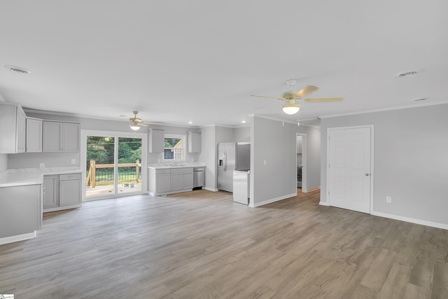 unfurnished living room with light wood-type flooring, ceiling fan, ornamental molding, and sink