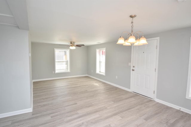 spare room with ceiling fan with notable chandelier and light hardwood / wood-style floors