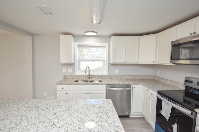 kitchen featuring white cabinetry, sink, light hardwood / wood-style floors, and appliances with stainless steel finishes