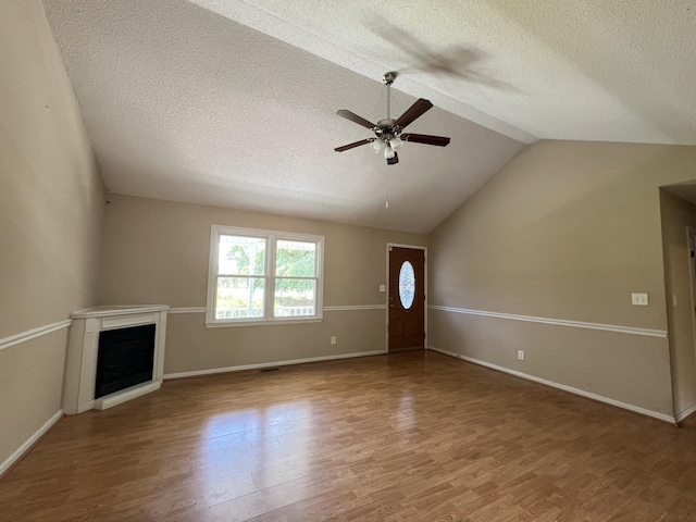 unfurnished living room with ceiling fan, wood-type flooring, a textured ceiling, and vaulted ceiling