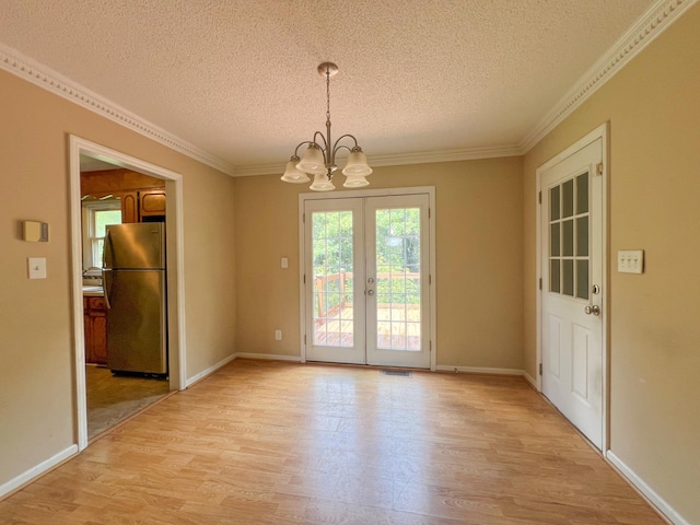 unfurnished dining area with crown molding, light hardwood / wood-style flooring, french doors, and an inviting chandelier