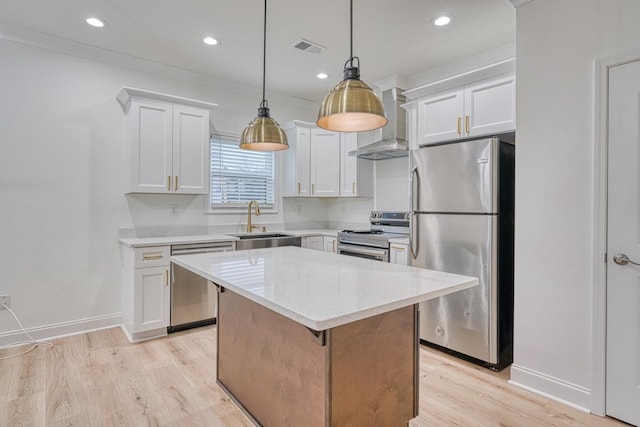 kitchen with white cabinets, sink, wall chimney exhaust hood, appliances with stainless steel finishes, and a kitchen island