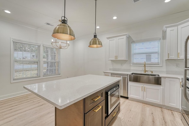 kitchen featuring a healthy amount of sunlight, a center island, white cabinets, and hanging light fixtures