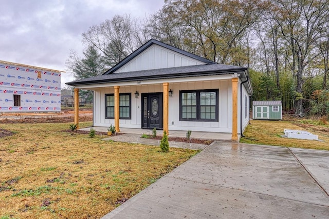 bungalow featuring covered porch, a front yard, and a storage unit