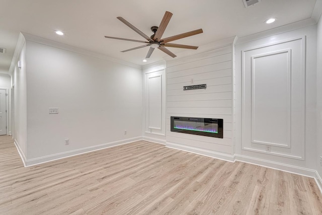 unfurnished living room with light wood-type flooring, a large fireplace, ceiling fan, and crown molding