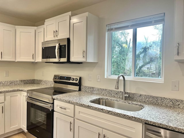 kitchen featuring a wealth of natural light, white cabinetry, sink, and appliances with stainless steel finishes