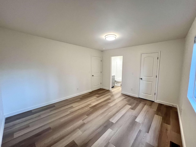 unfurnished bedroom featuring hardwood / wood-style flooring and connected bathroom