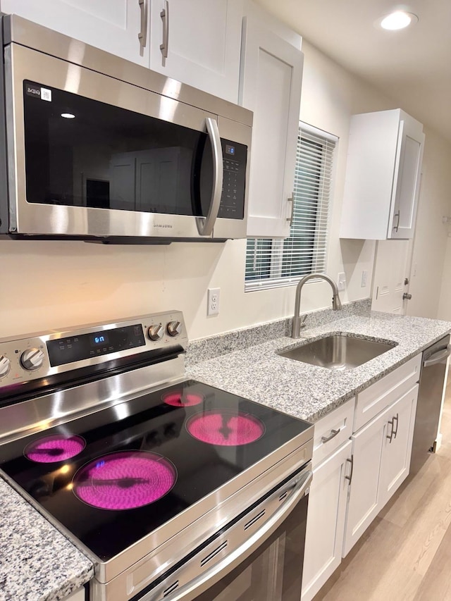 kitchen with appliances with stainless steel finishes, white cabinetry, and sink