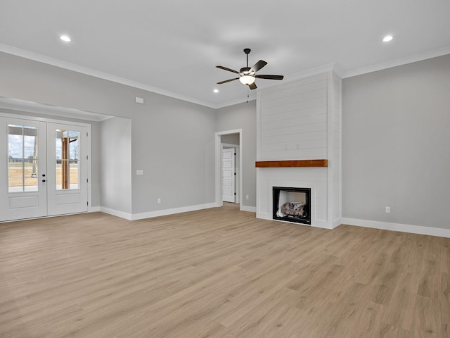 unfurnished living room featuring ceiling fan, a large fireplace, french doors, light hardwood / wood-style flooring, and crown molding