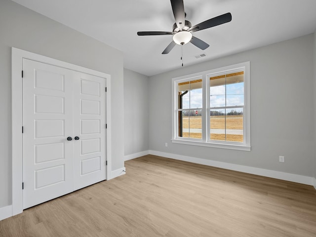 unfurnished bedroom featuring ceiling fan, a closet, and light wood-type flooring