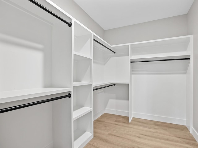 walk in closet with light hardwood / wood-style flooring