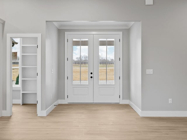 doorway to outside with crown molding, french doors, and light wood-type flooring