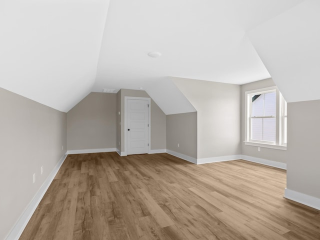 bonus room with vaulted ceiling and light wood-type flooring