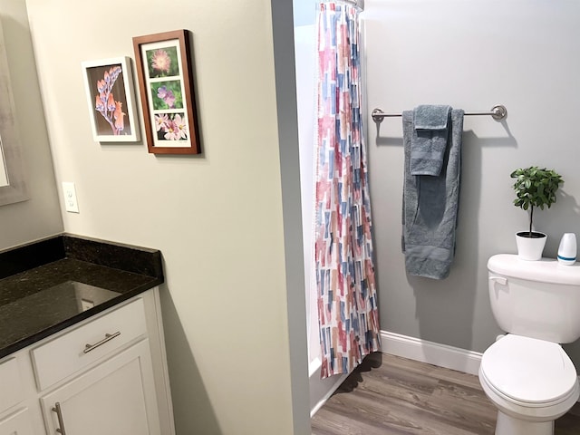 bathroom with hardwood / wood-style floors, vanity, toilet, and walk in shower