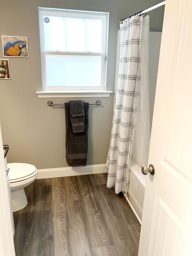 bathroom featuring wood-type flooring, shower / bath combo, and toilet