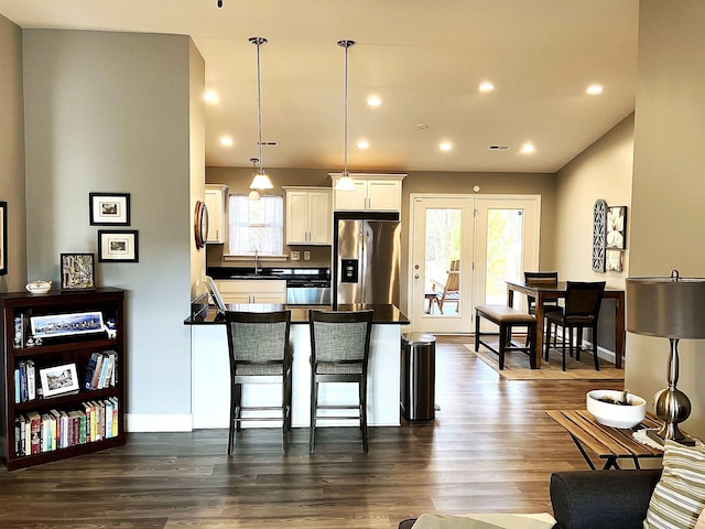 kitchen with white cabinets, dark hardwood / wood-style floors, decorative light fixtures, a kitchen bar, and stainless steel fridge with ice dispenser