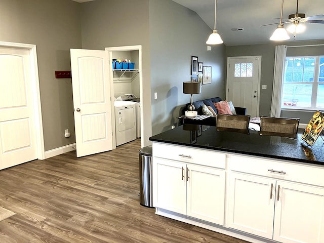 kitchen with separate washer and dryer, pendant lighting, vaulted ceiling, white cabinets, and hardwood / wood-style flooring