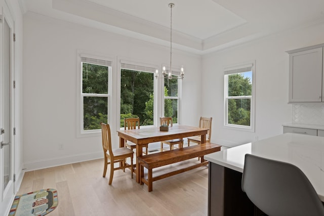 dining space featuring a tray ceiling, light hardwood / wood-style flooring, a wealth of natural light, and ornamental molding